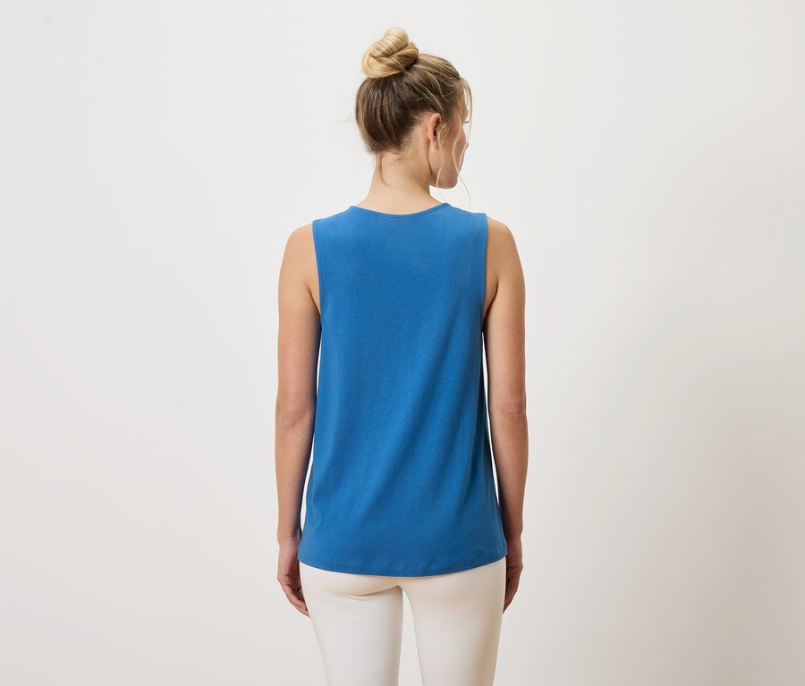 Vue arrière d'une femme portant un chignon, un débardeur bleu et un pantalon blanc.