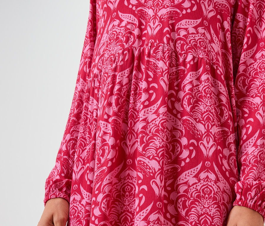 Gros plan d'une robe rouge à manches longues avec un motif floral rose.