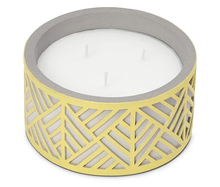 Une grande bougie à trois mèches dans un récipient jaune avec un motif géométrique et un bord gris.