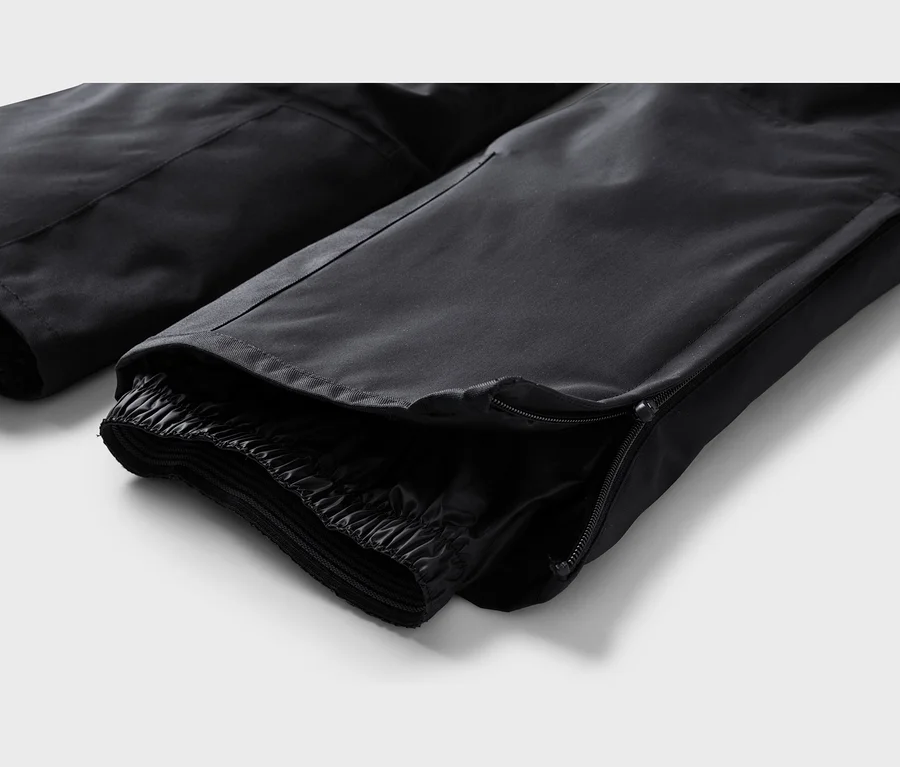Gros plan de la cheville d'un pantalon noir avec une fermeture éclair partiellement ouverte révélant un ourlet intérieur élastique.