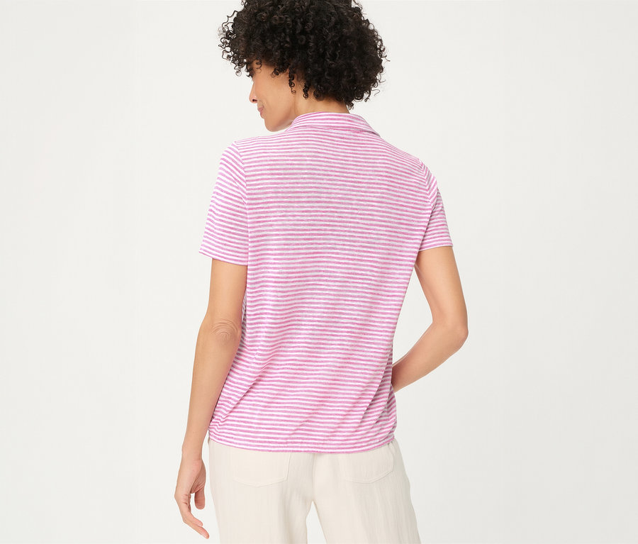 Femme de dos portant un polo Olsen rayé rose et blanc et un pantalon clair.