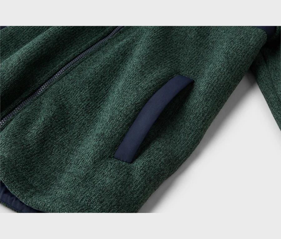 Gros plan d'une veste polaire chinée vert foncé avec une fermeture éclair foncée à gauche et une ouverture de poche bordée de bleu foncé à droite.
