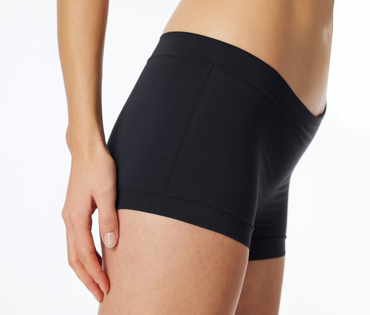 Vue latérale d'une personne portant un boxer noir ajusté, avec une main posée sur la cuisse.