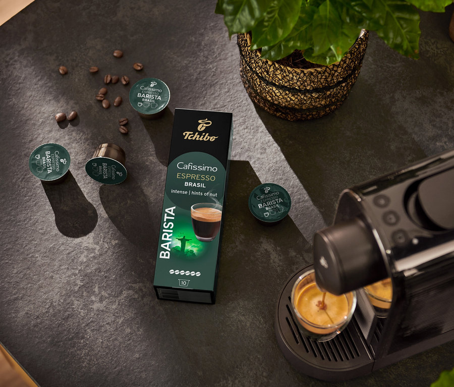 Machine à expresso remplissant une tasse. À l'arrière-plan, paquet de 10 capsules Espresso Brasil et grain de café.