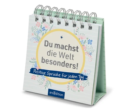 Sur une table se trouve un calendrier de table avec l'inscription "Tu rends le monde spécial ! Des dictons positifs pour chaque jour".