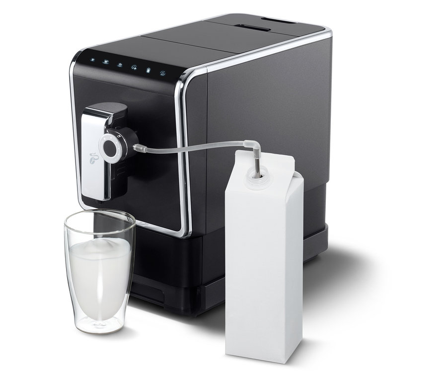 Machine à café entièrement automatique de Tchibo « Esperto Pro » anthracite avec du lait dans un verre et un carton.