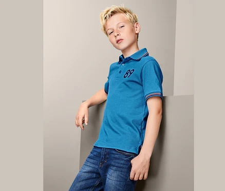 Garçon portant un polo bleu avec le numéro 89 et un jean.