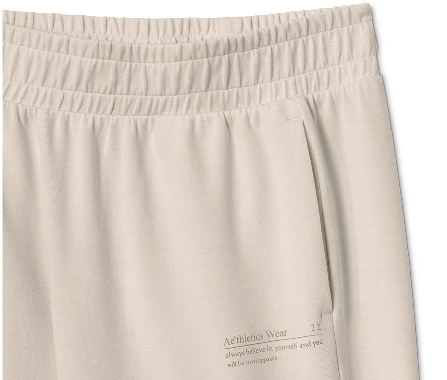 Détail d'un pantalon molletonné très doux beige avec poche et inscription.