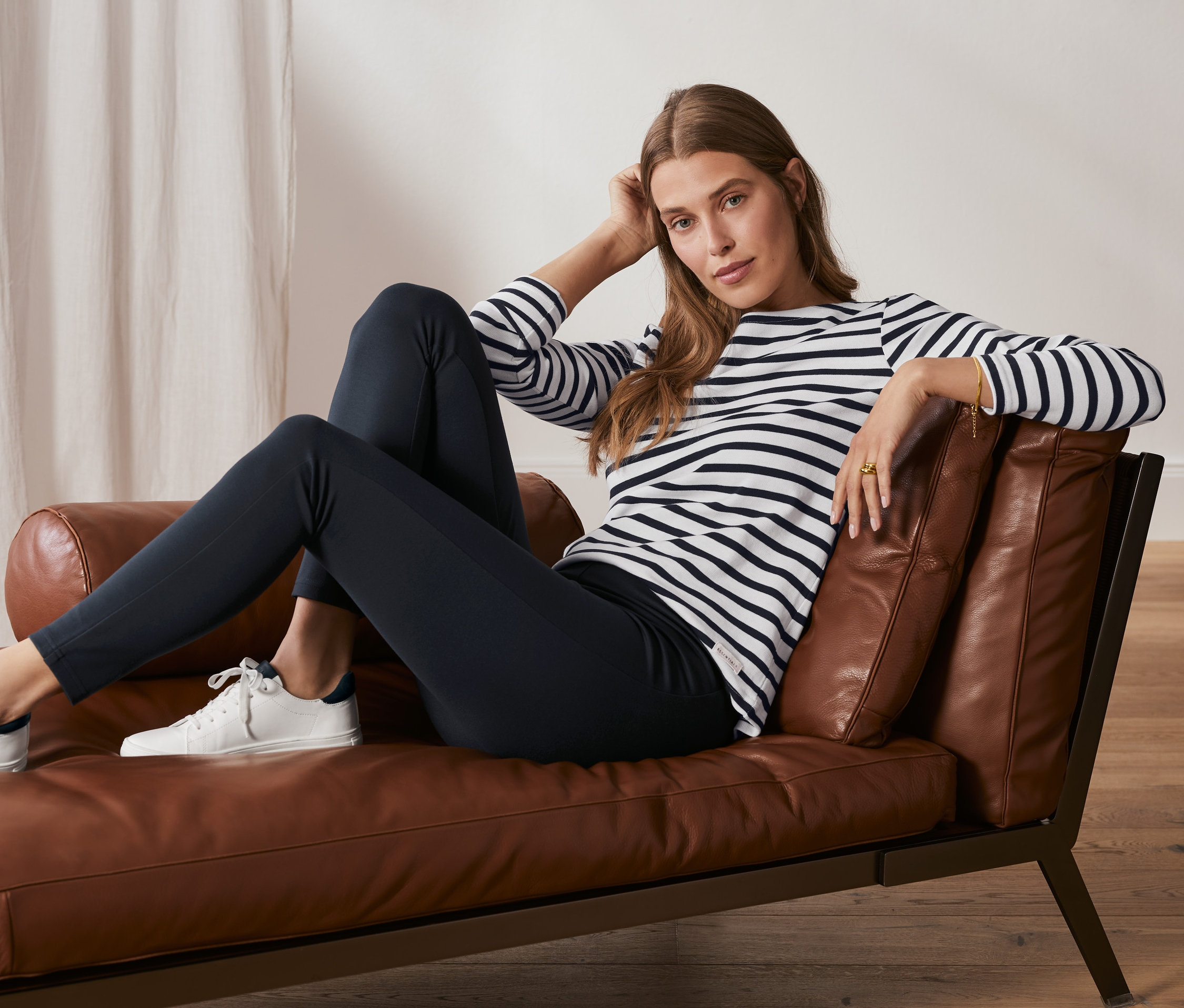 Femme assise sur un fauteuil en cuir portant un legging basique en jersey lourd bleu foncé.