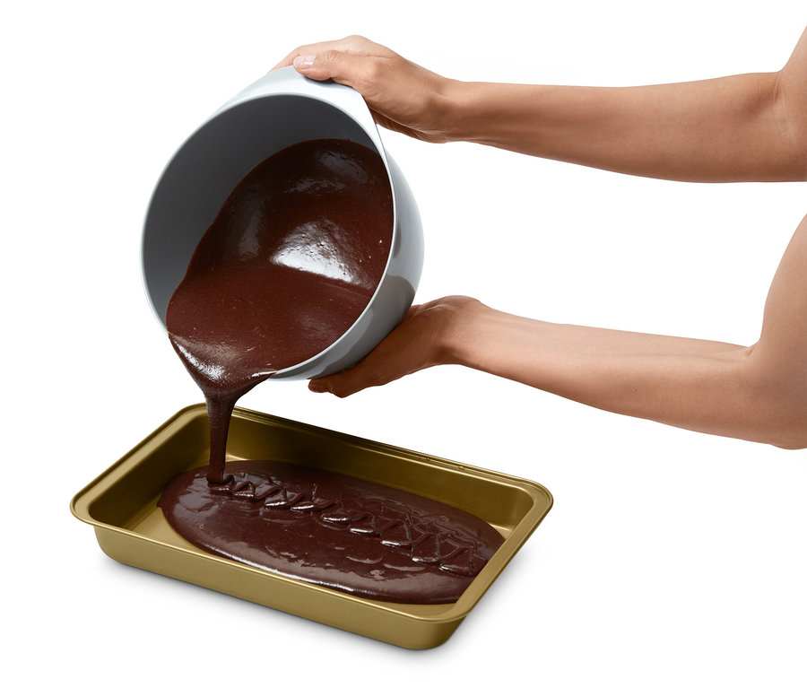 De la pâte à gâteau brune est versée d'un bol dans un moule à brownie.
