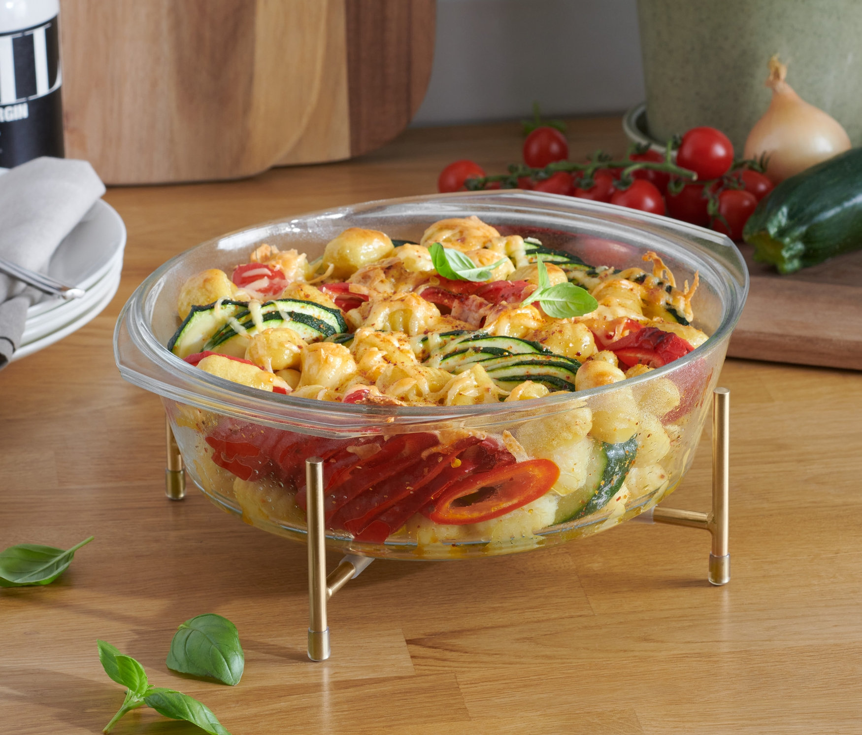 Gratin de légumes dans un plat à gratin en verre avec structure posé sur une planche en bois.