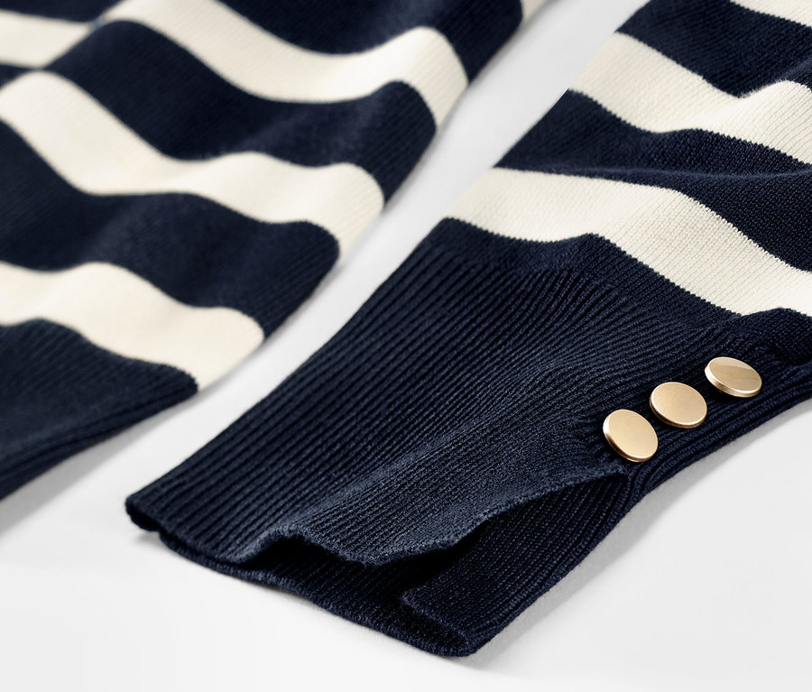 Détail d'un pull en maille fine rayé bleu foncé avec des boutons sur la manche.