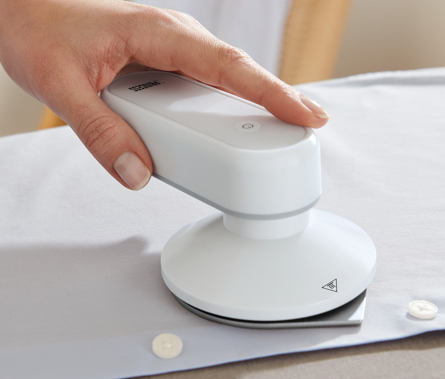 Une main repasse une chemise blanche avec un fer à repasser de voyage Princess avec Power Bank.