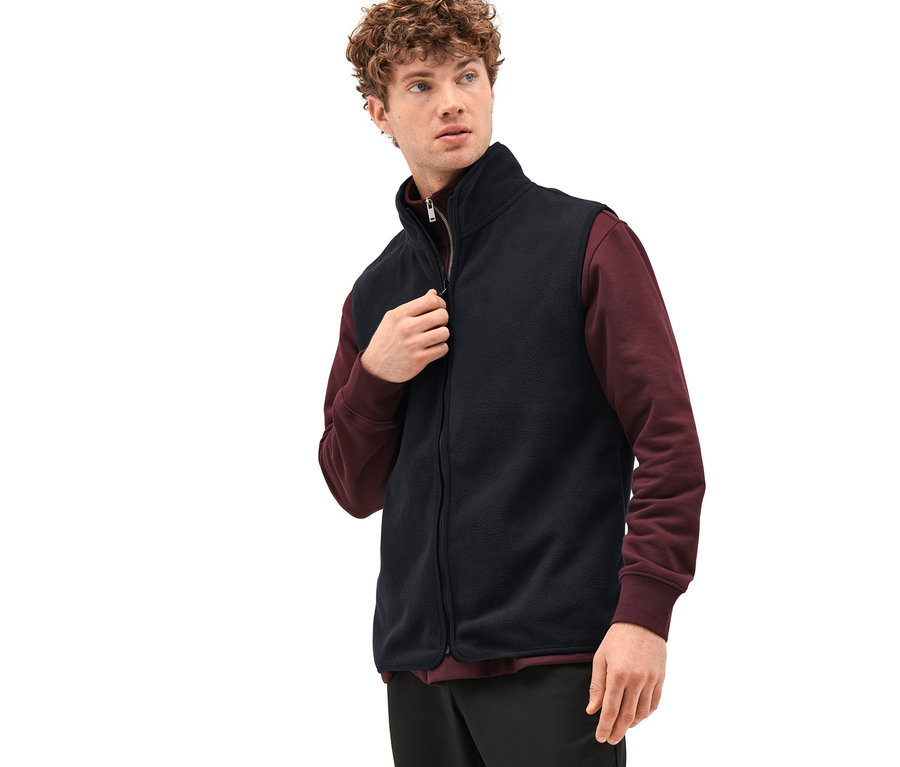 Homme fermant une veste d'extérieur noire avec gilet.