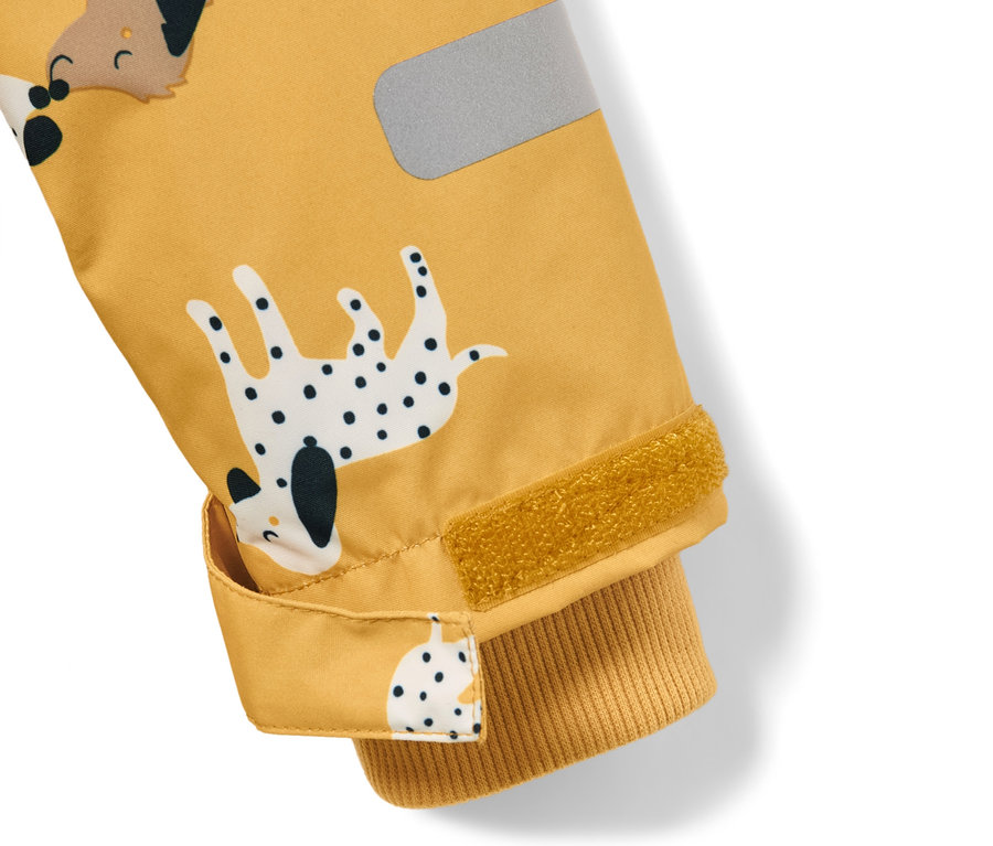 Gros plan sur une combinaison de pluie jaune avec un imprimé de chien et une bande réfléchissante.