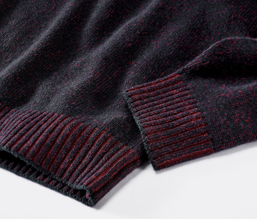 Gros plan sur un pull en laine bleu marine et rouge.