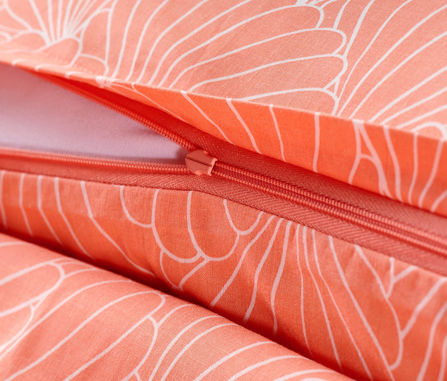 Détail de la parure de lit en renforcé couleur saumon avec fermeture éclair et motif floral blanc.