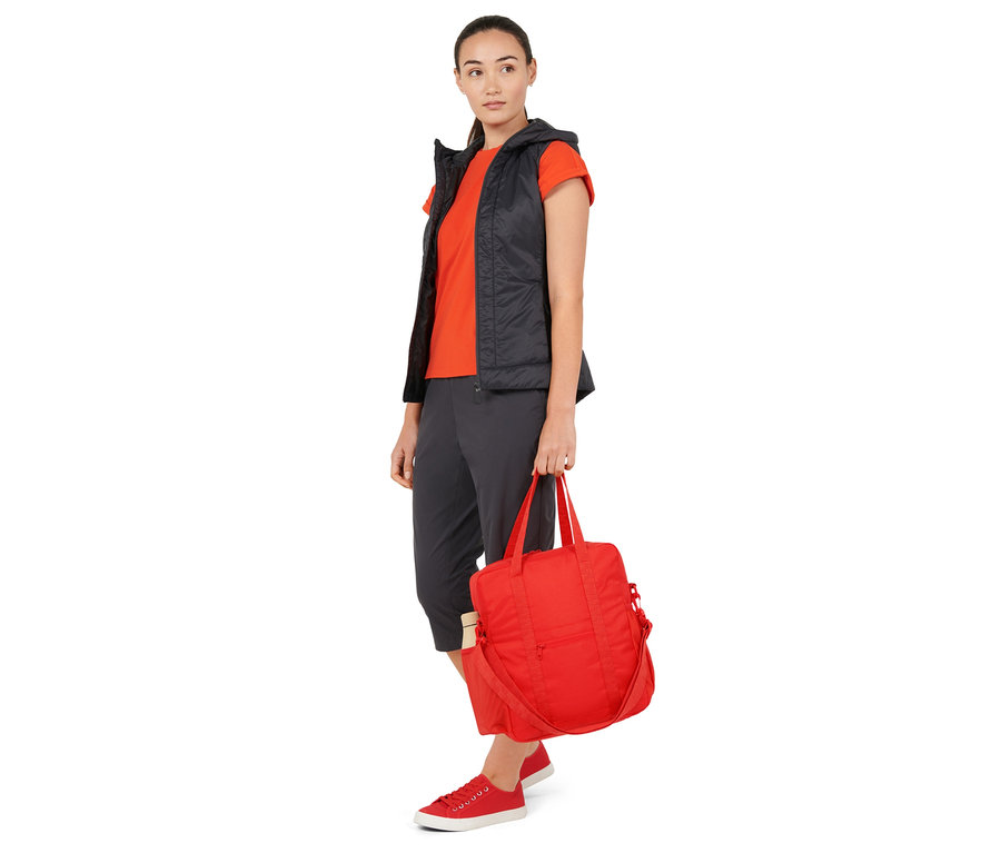 Femme tenant un sac à bandoulière rouge pour vélo.