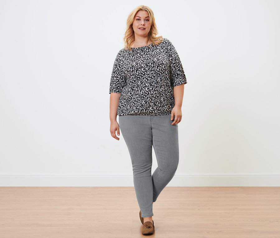 Femme posant en blouse imprimée florale, tregging gris chiné et loafers en cuir velours.