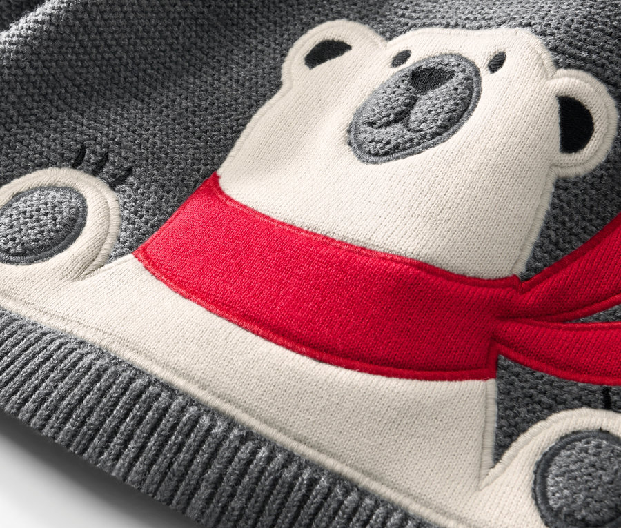 Gros plan sur un pull en maille enfant orné d'un ours polaire avec une écharpe rouge.