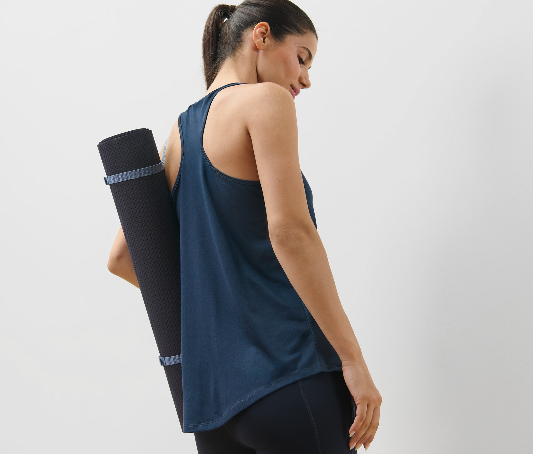 Femme portant un tapis de yoga dans un 2	-shirts de sport bleu et bleu foncé.