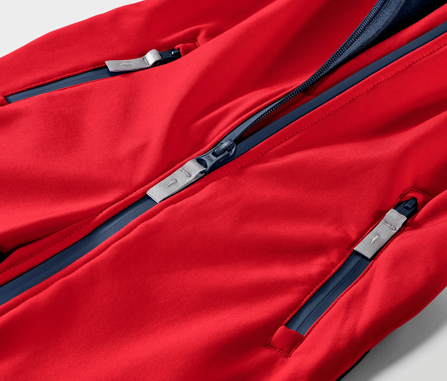 Détail d'une combinaison en softshell pour enfant, rouge et bleue.