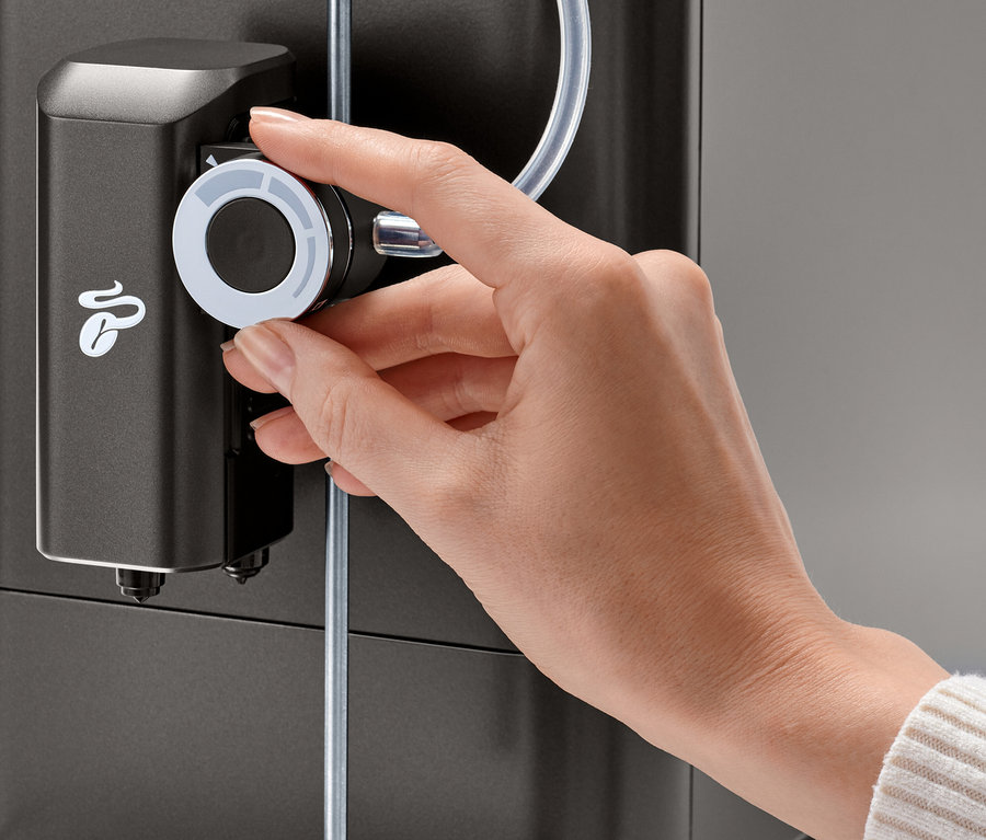 Une main tourne le bouton de réglage de la mousse de lait sur une machine à café « Esperto 2 Milk » Granite Black.