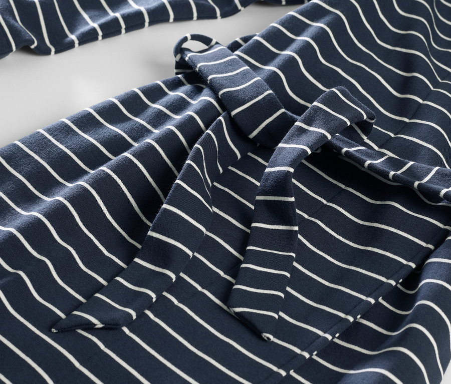 Détail d'une robe de chambre bleu marine rayée blanche.