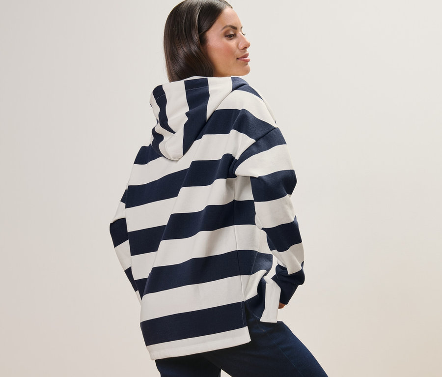 Femme posant dans un sweat à capuche rayé.