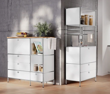 Dans la pièce, un meuble en métal « CN3 » avec plateau en bois, 1 abattant et 4 tiroirs, blanc et une étagère en métal « CN3 » avec 1 abattant et 2 tiroirs.
