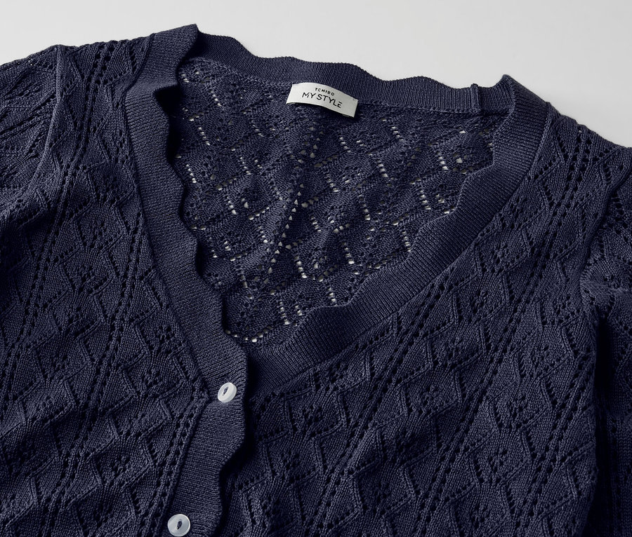 Gros plan sur une jaquette en maille bleu foncé à motif ajouré.