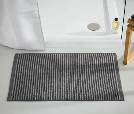 Un tapis de douche de haute qualité, anthracite, est posé sur le sol à côté d'une douche.