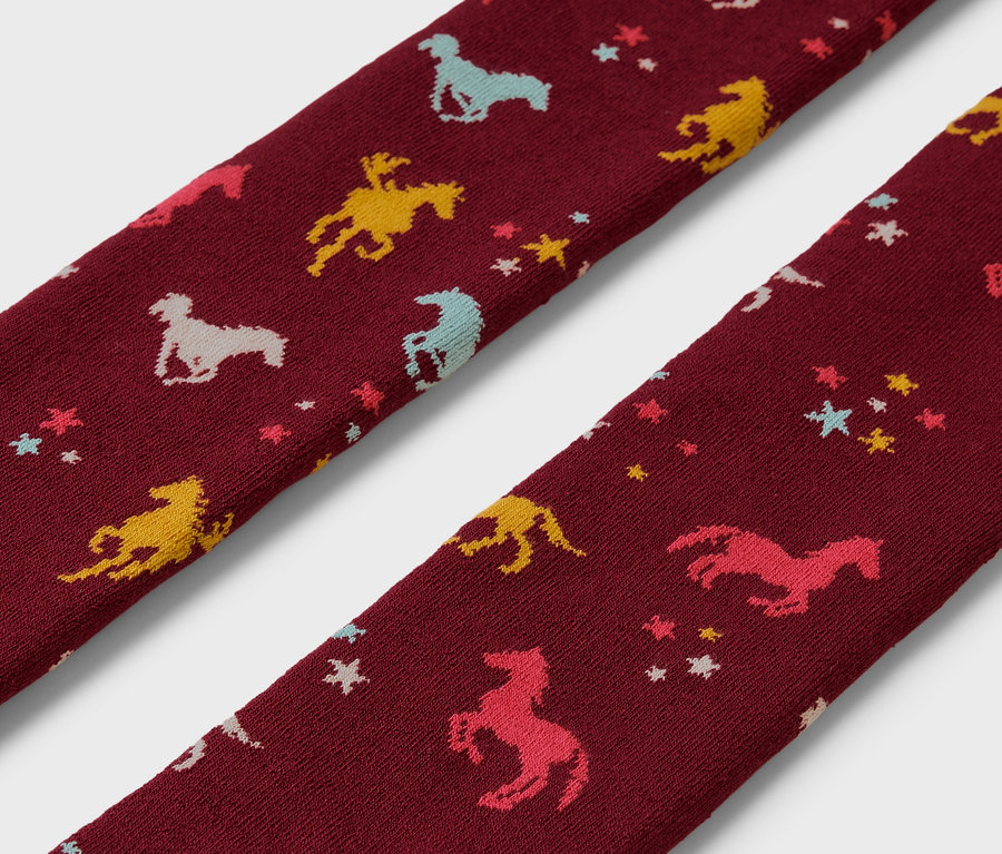 Gros plan sur deux collants thermiques pour enfant avec des motifs de chevaux et d'étoiles.