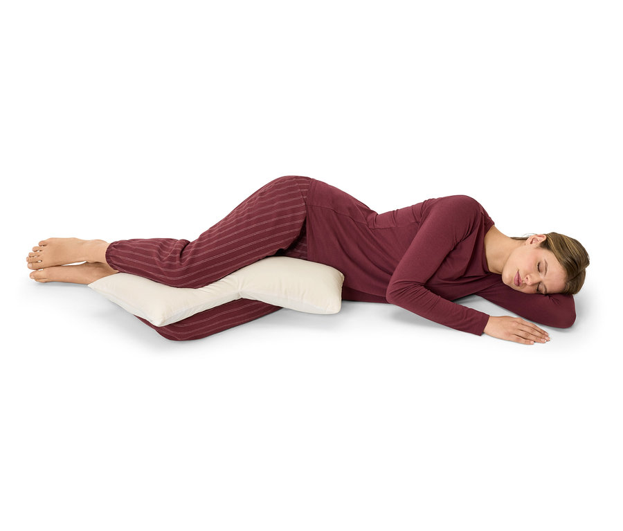 Femme couchée sur le côté embrassant un oreiller.