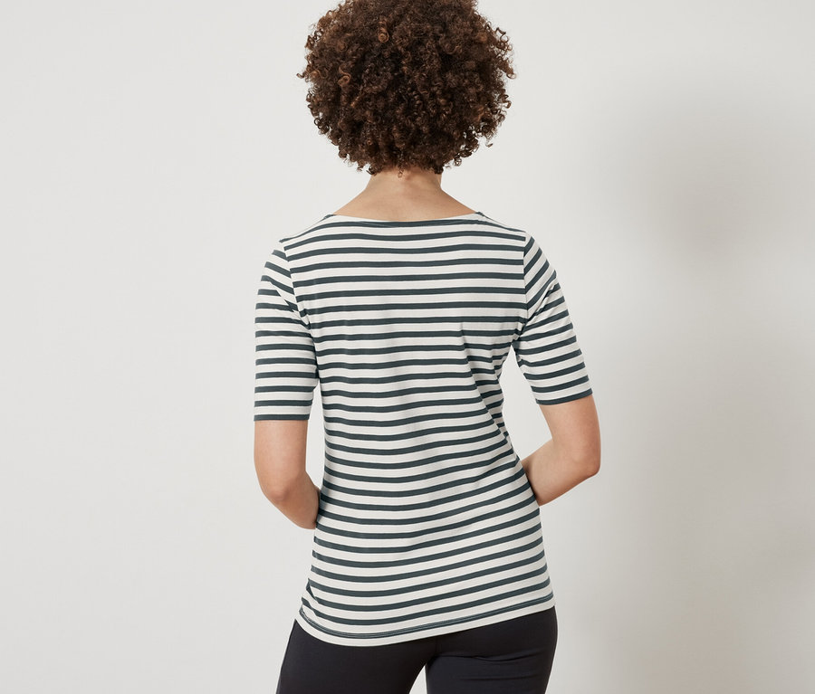 Vue arrière d'une femme aux cheveux bruns et bouclés portant un t-shirt à demi-manches vert à rayures et un pantalon noir.