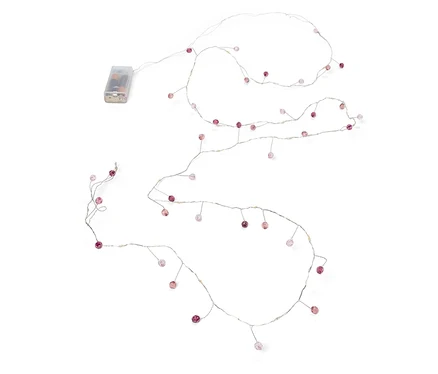 Guirlande lumineuse avec de petites perles roses et un bloc d'alimentation à piles sur fond blanc.