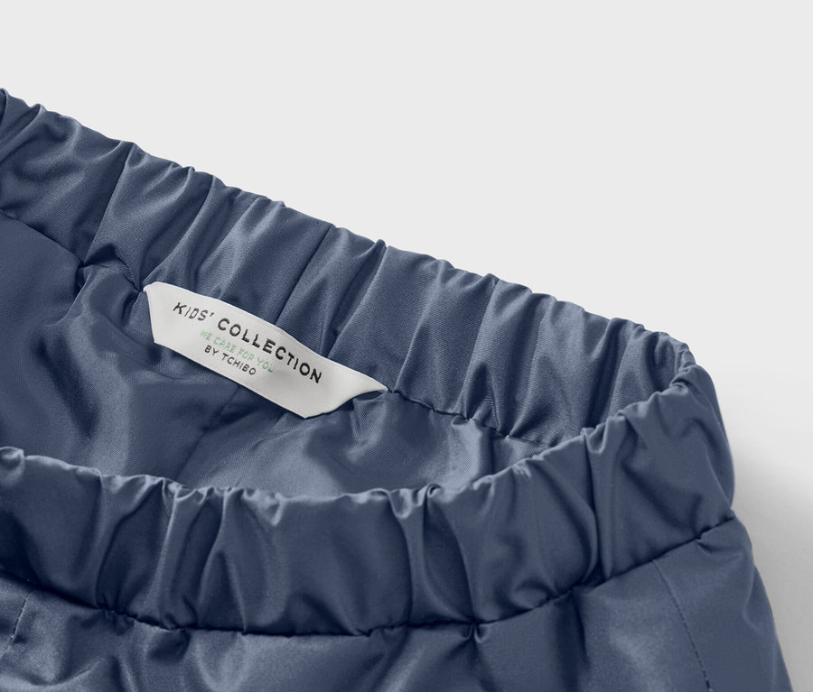 Gros plan sur un pantalon bleu pour enfants avec une taille élastique et une étiquette indiquant « Kids' Collection ».
