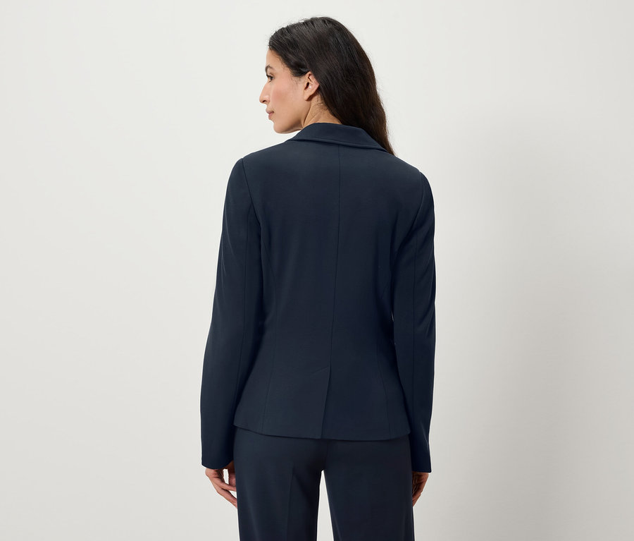 Femme vue de dos portant un blazer et un pantalon bleu marine.