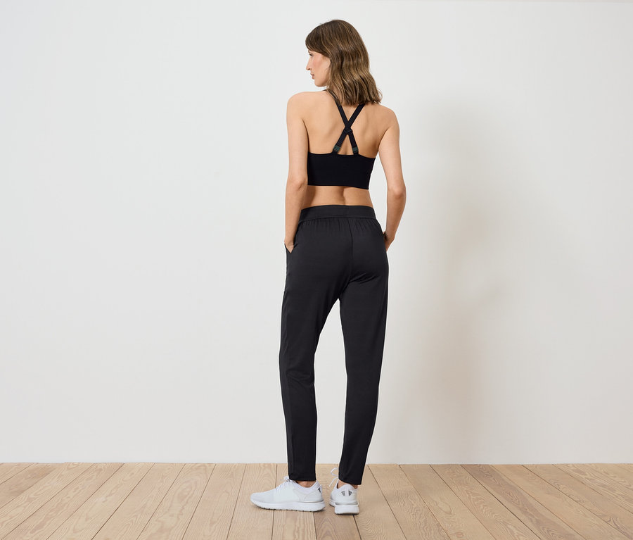 Femme portant un haut de sport et un pantalon noirs, dos à la caméra.