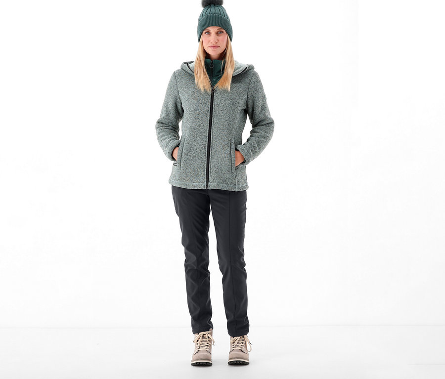 Femme debout portant un pantalon softshell CMP, une veste et un bonnet.