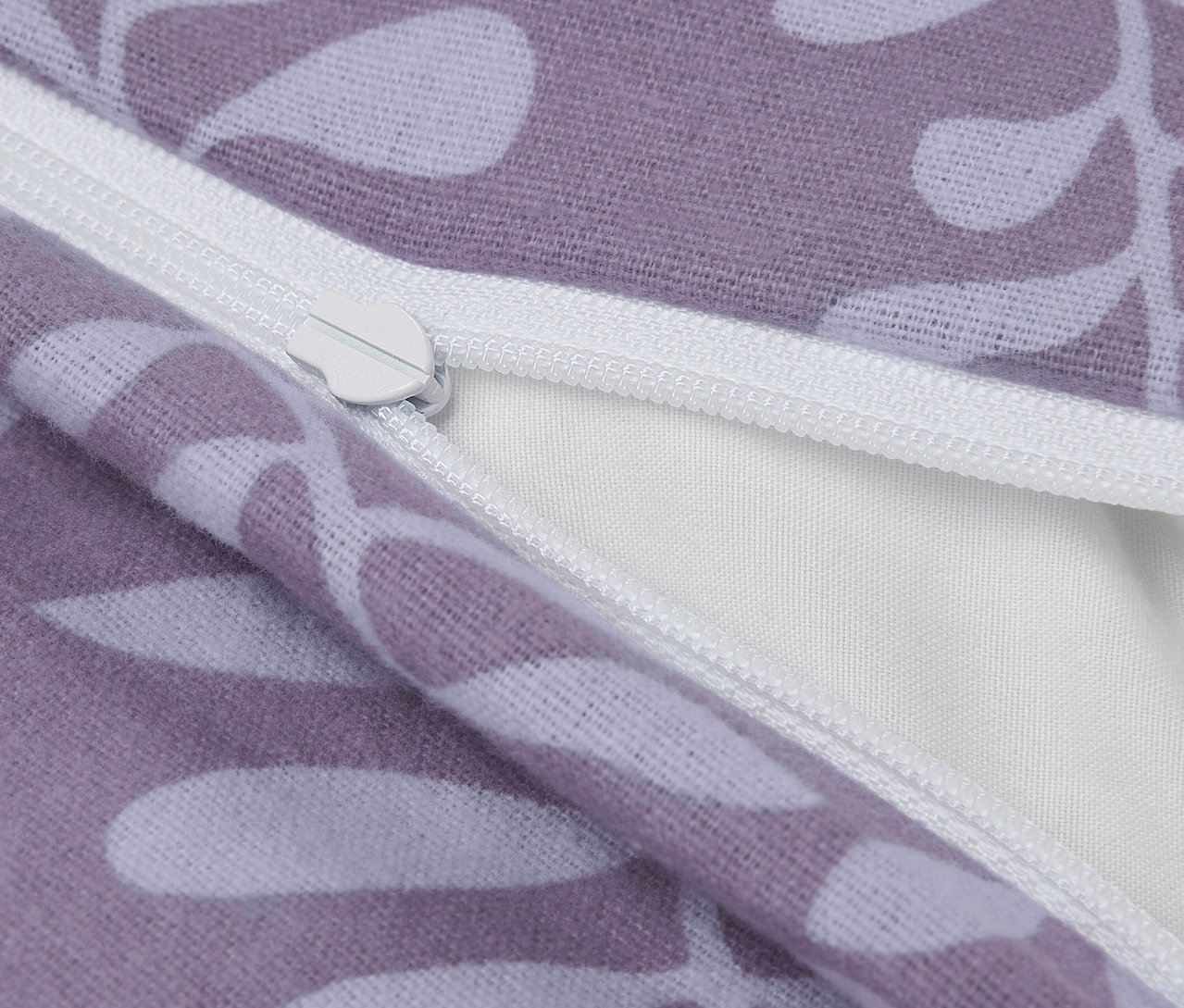 Gros plan sur une taie d'oreiller violette avec des feuilles blanches et une fermeture éclair.