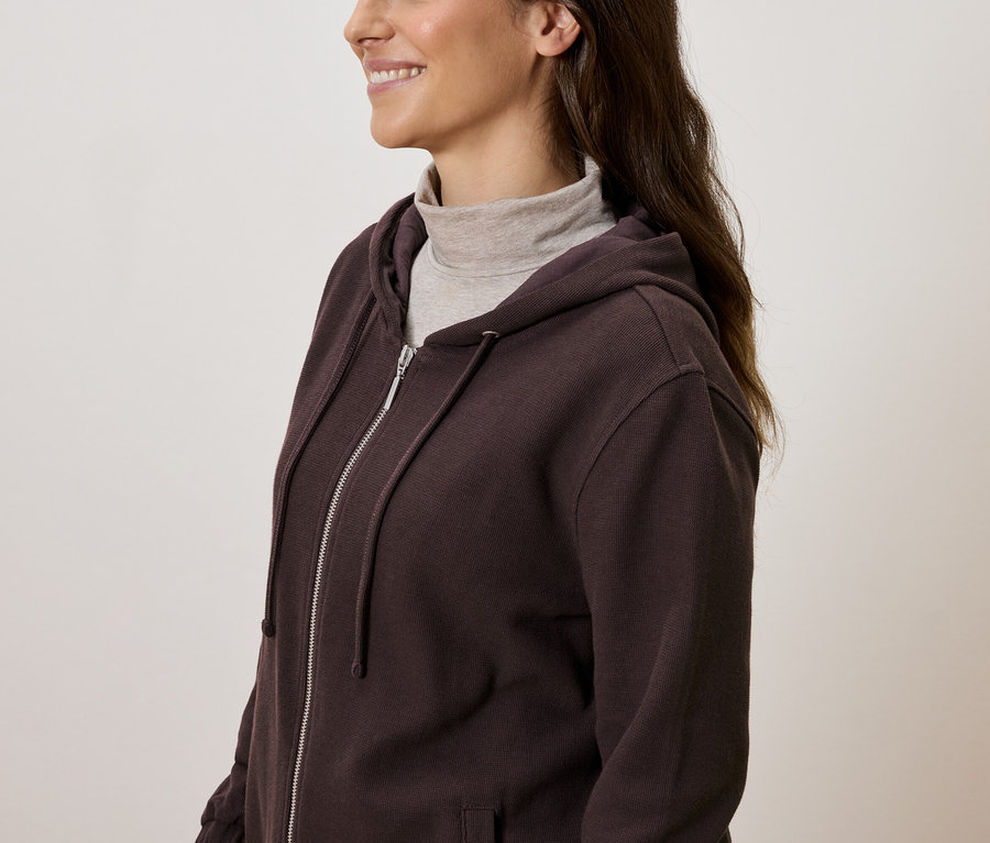 Femme portant un sweat à capuche marron zippé avec un col roulé.