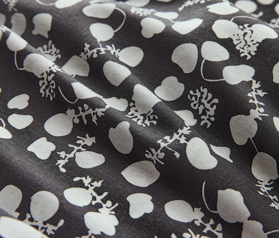 Gros plan d'un tissu à fleurs blanches et points sur fond foncé.