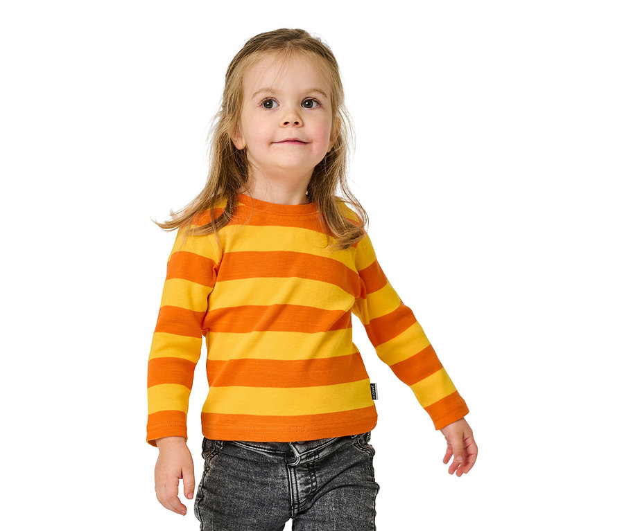 Fillette souriante portant un t-shirt rayé orange et jaune à manches longues et un jean.