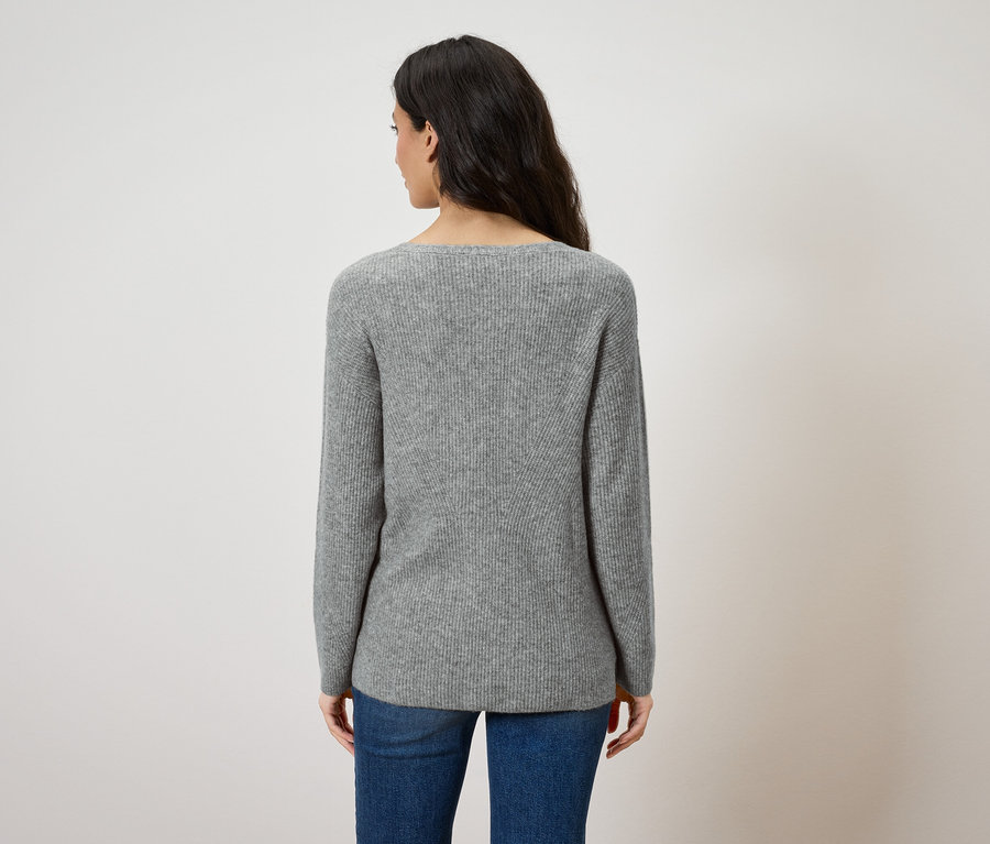 Vue de dos d'une femme aux cheveux foncés portant un pull gris et un jean bleu.