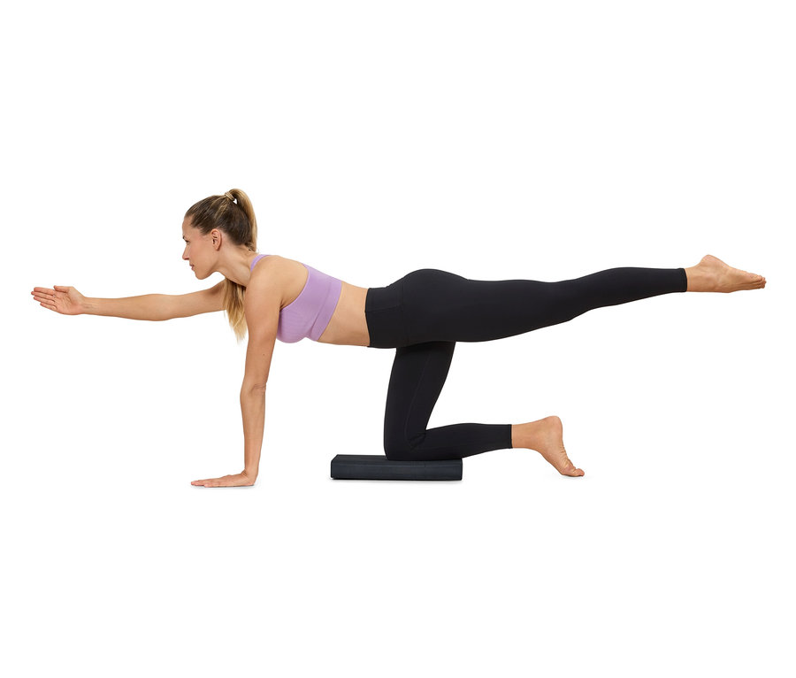 Une femme fait du yoga sur un tapis et porte des vêtements de sport.