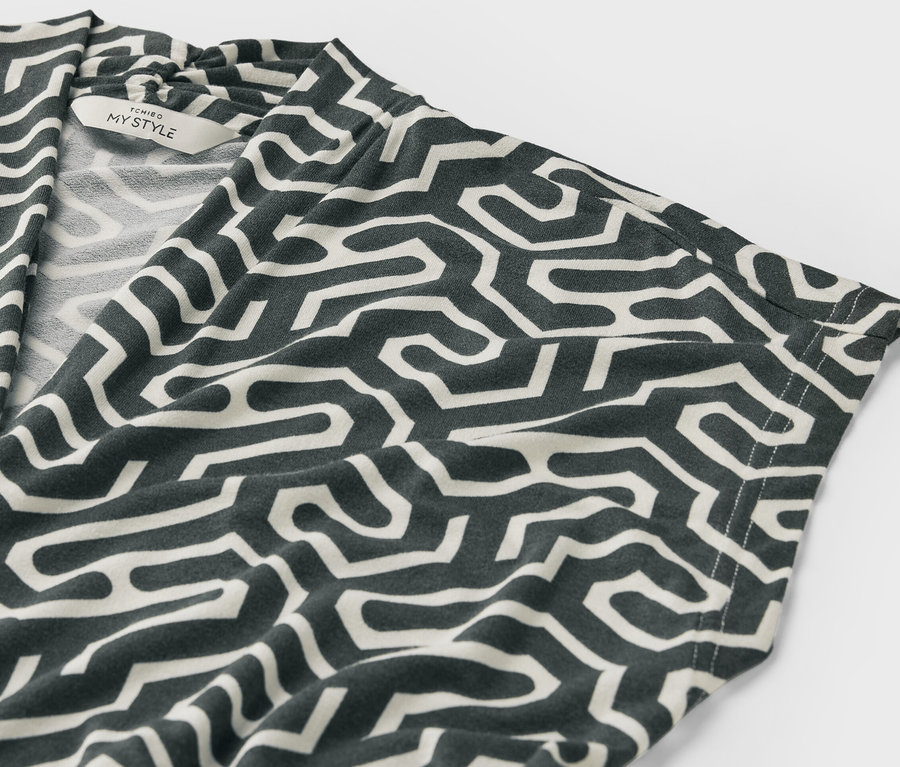 Gros plan sur une blouse verte à encolure en V avec motif.