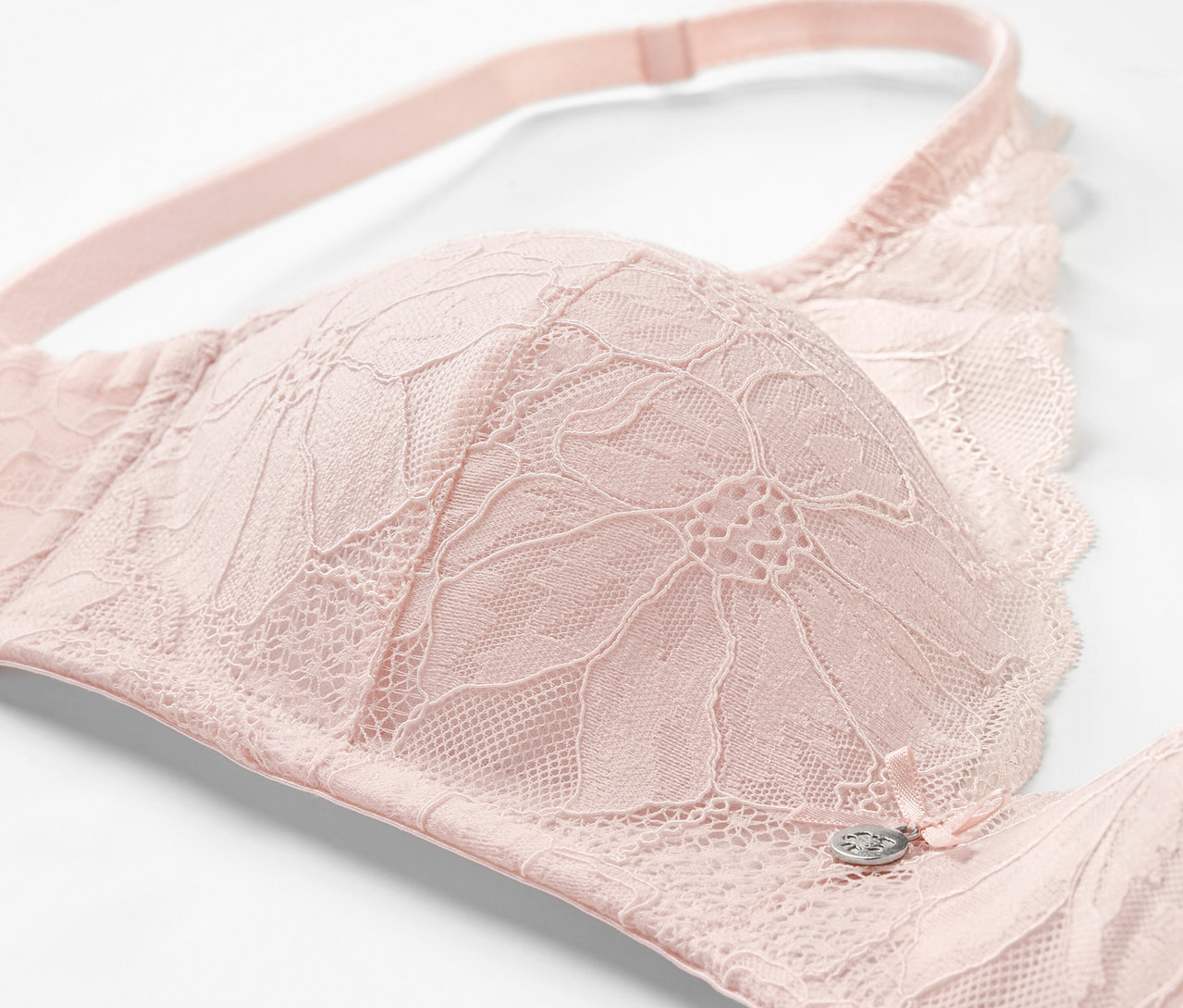 Gros plan d'un soutien-gorge à coques souples rose avec détails en dentelle.