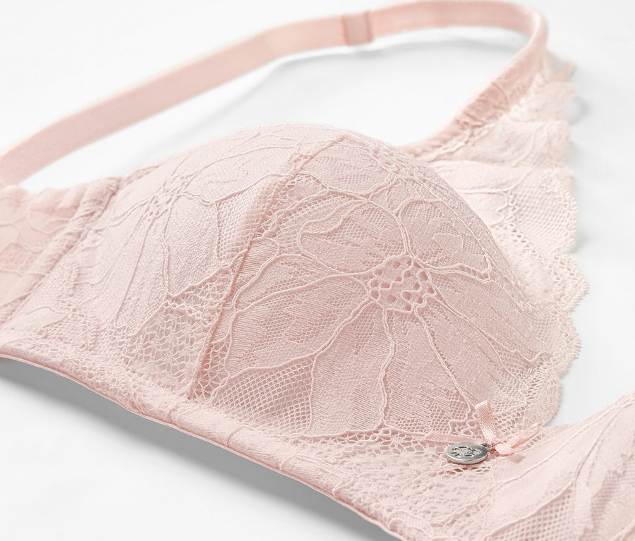 Gros plan d'un soutien-gorge à coques souples rose avec détails en dentelle.