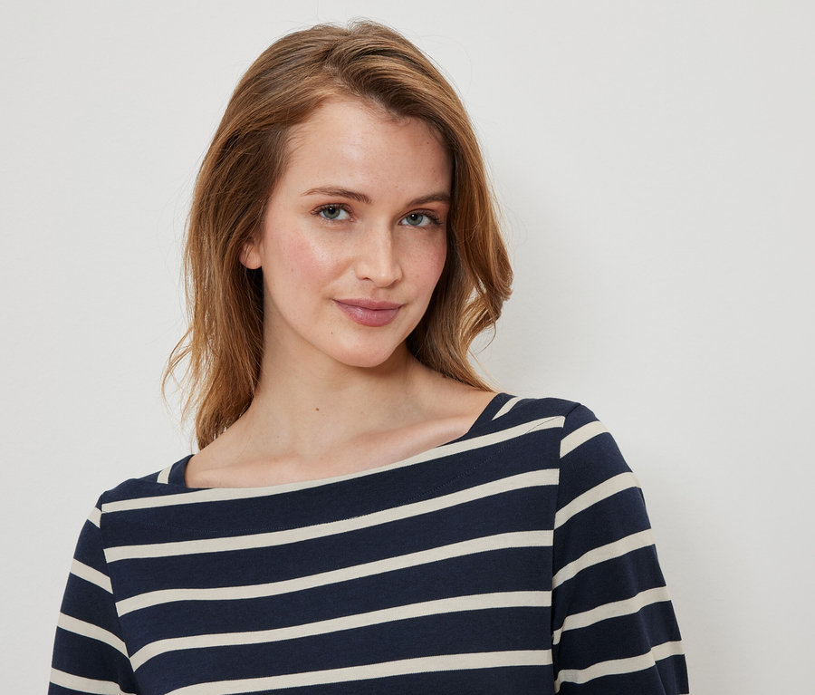 Portrait d'une femme aux cheveux bruns et aux yeux bleus portant un haut rayé bleu et blanc.